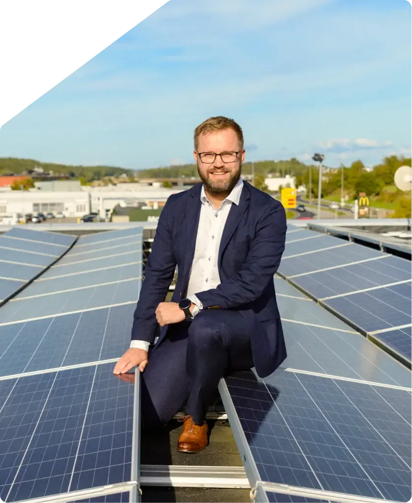 An installer sitting on a roof beside newly laid solar panels.