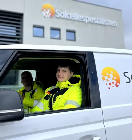 Two installers in yellow work jackets sitting ready in one of Solcellespesialisten's service vans.